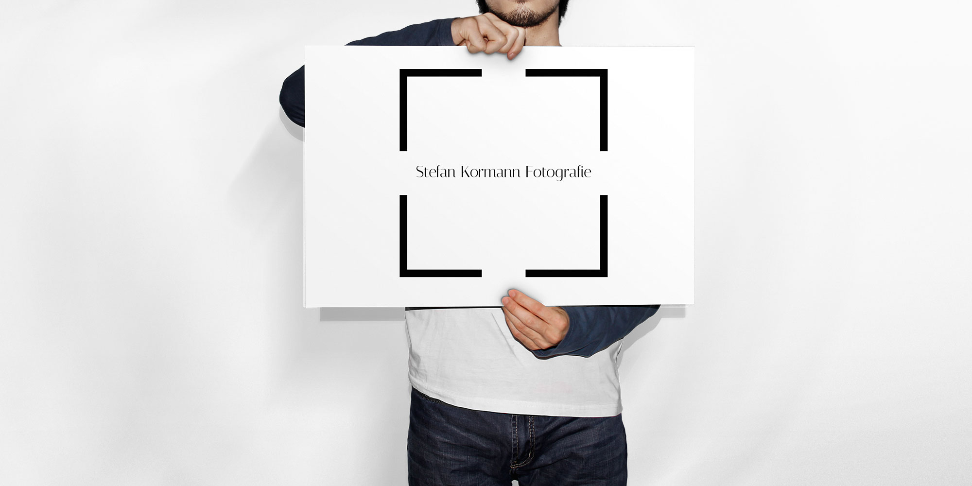 Ein Mann hält eine Leinwand mit dem Stefan Kormann Fotografie Logo